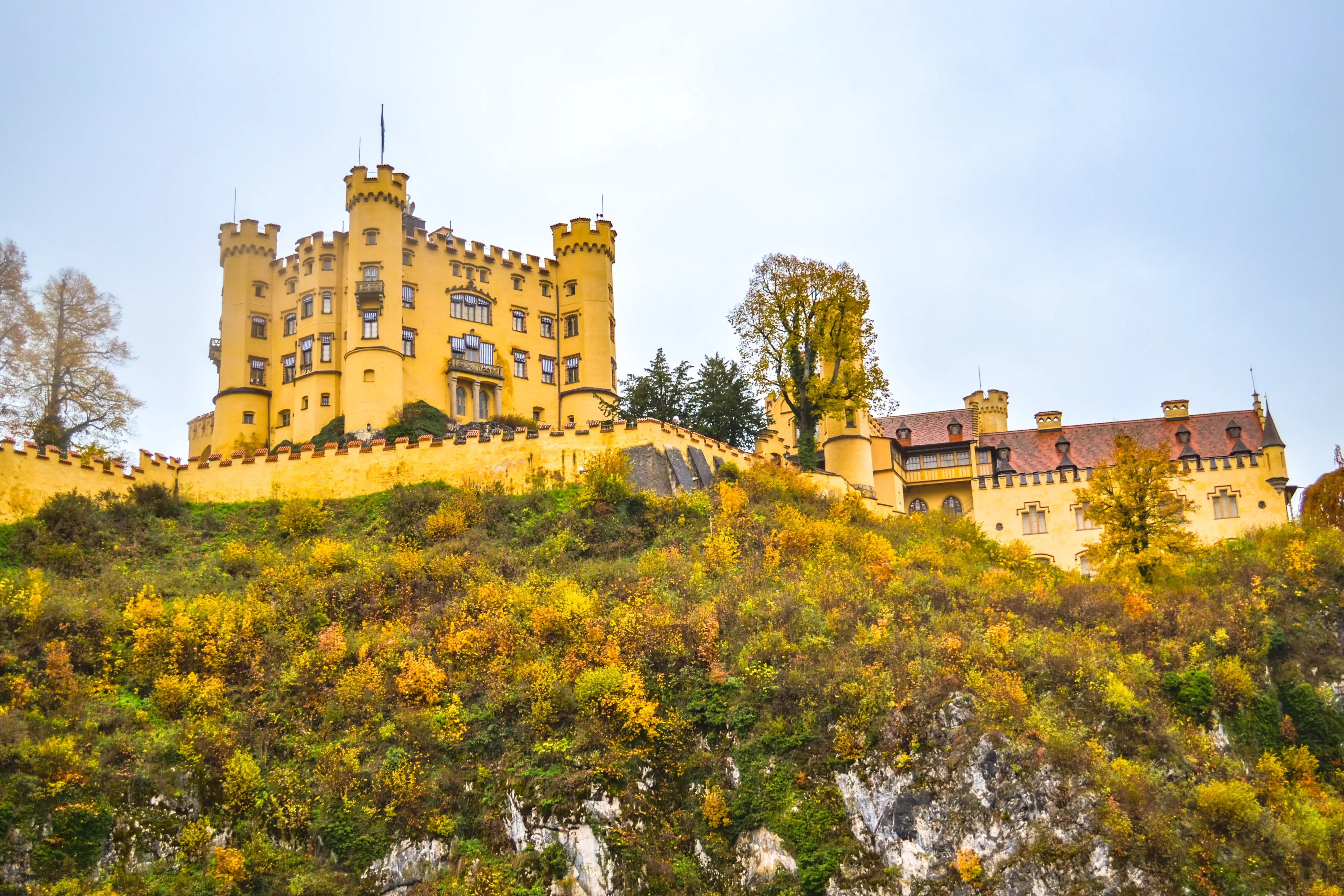 Deutschland, Schwangau, Schloss Hohenschwangau: Ein Schloss auf einem Hügel mit einem gelben Gebäude oben.